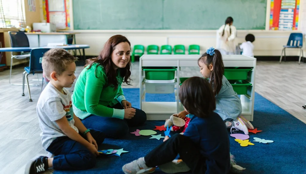 Older woman sitting with children watching them play