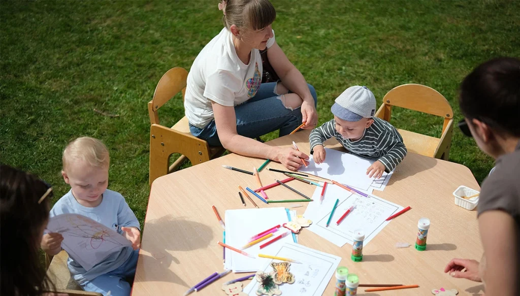 parents with children coloring on a table outside