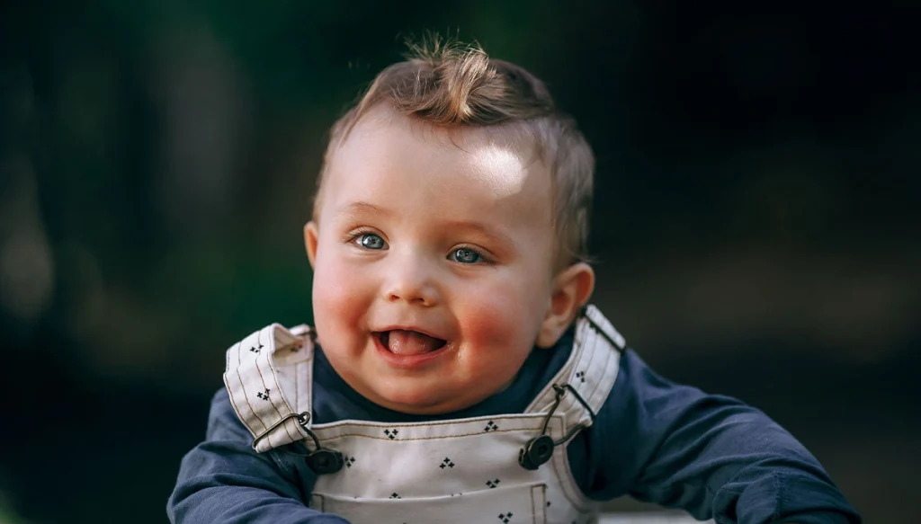 A cheerful baby smiling outdoors, 