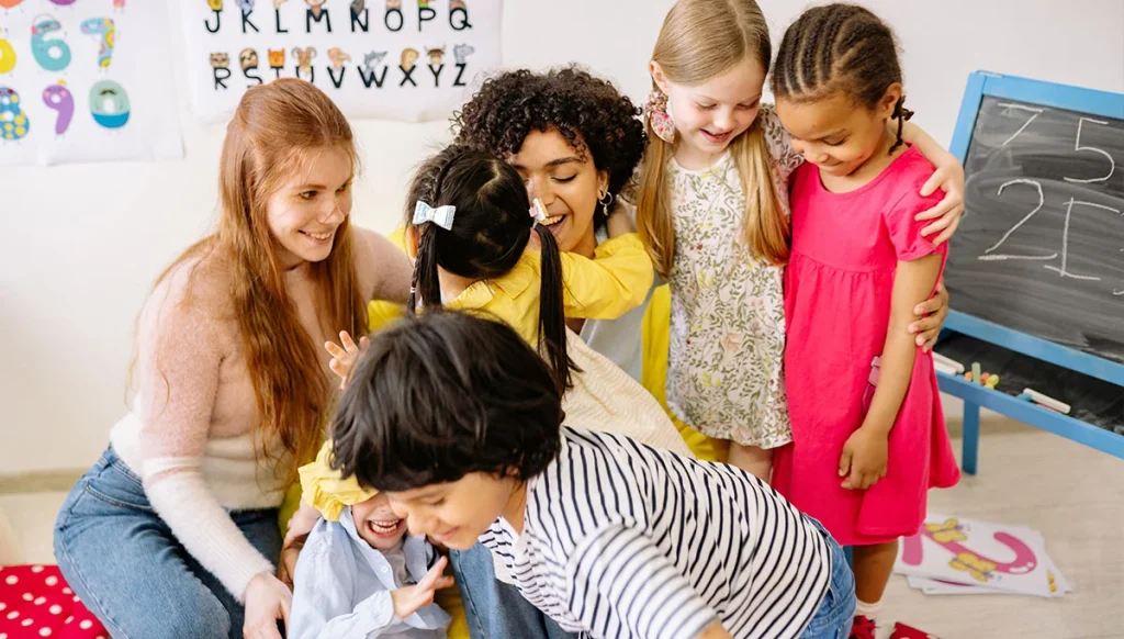 children group hug teacher in class